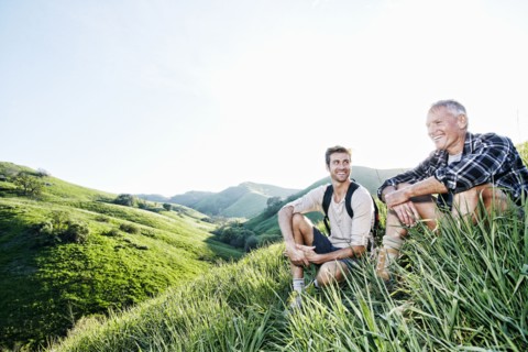 Caucasian father and son sitting on grassy hillside