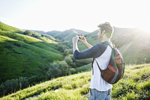 Caucasian man photographing scenic view from rural hilltop