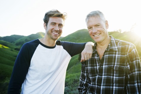 Caucasian father and son smiling on rural hilltop