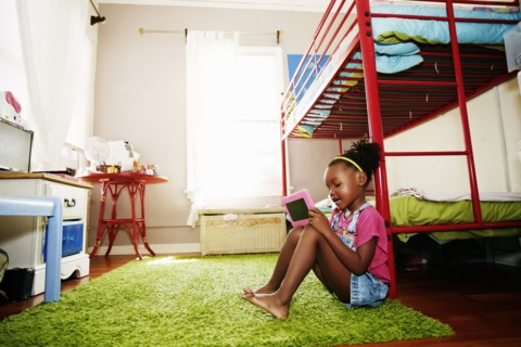 Black girl using digital tablet in bedroom