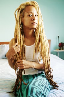 Black woman with dreadlocks sitting on bed