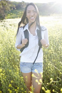 Mixed race woman carrying backpack in field