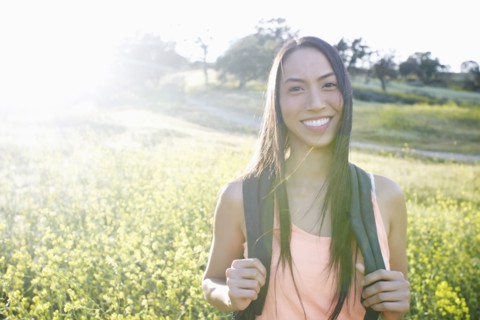 Mixed race woman carrying backpack in field