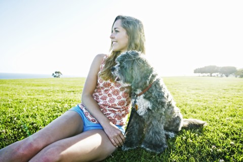 Caucasian woman sitting in field with dog