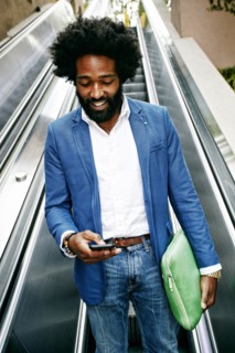 Mixed race businessman using cell phone on escalator
