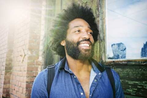 Mixed race musician carrying guitar outdoors