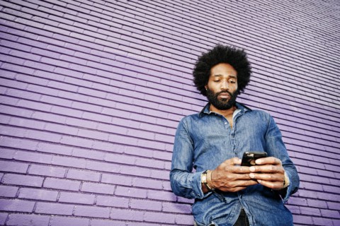 Mixed race man using cell phone outdoors