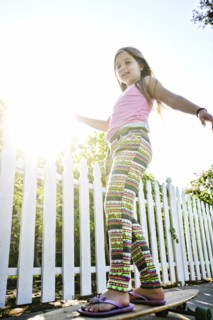 Caucasian girl riding skateboard on sidewalk