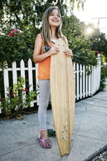 Caucasian girl holding skateboard on sidewalk