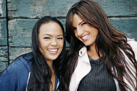 Women smiling at wooden wall