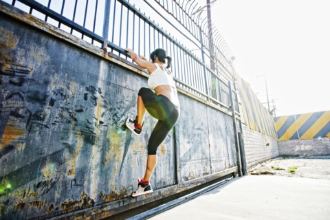 Mixed race woman climbing gate