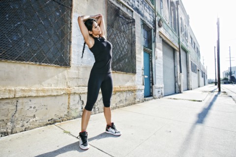 Mixed race woman stretching on sidewalk
