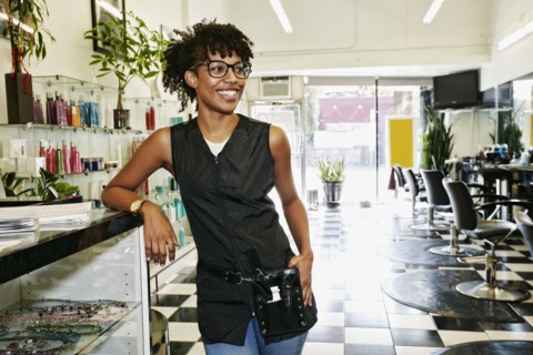 Mixed race hairstylist smiling in salon