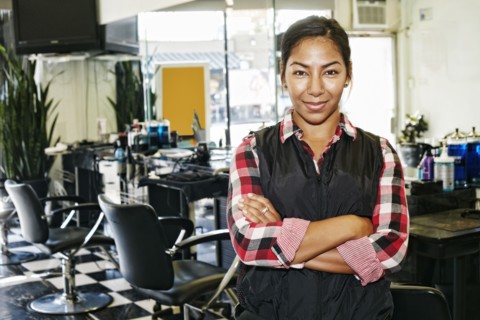 Hispanic hairstylist smiling in salon