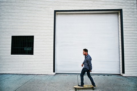 Caucasian man riding skateboard on sidewalk