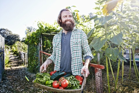 Caucasian man holding basket of vegetables in garden