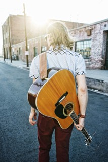 Caucasian man carrying guitar outdoors