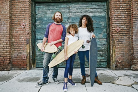 Family holding skateboards on sidewalk