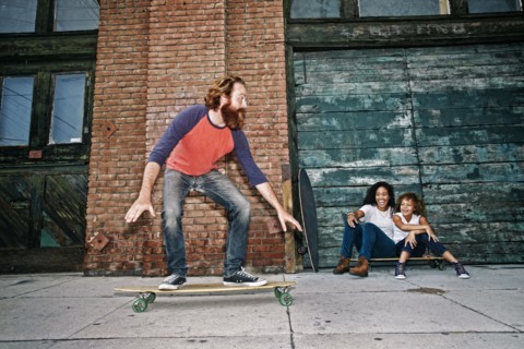 Family riding skateboards on sidewalk