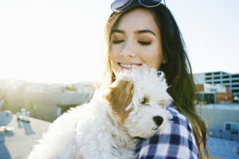 Mixed race woman holding dog on urban rooftop