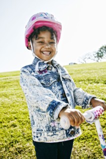 Black girl wearing helmet on scooter