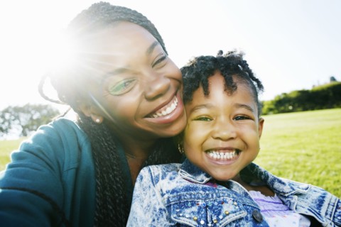 Black mother and daughter smiling outdoors