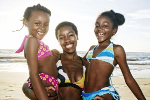Black mother holding daughters on beach
