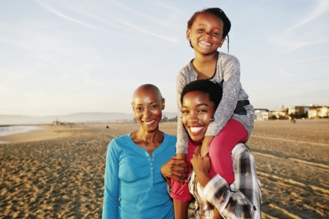Three generations of Black women smiling on beach