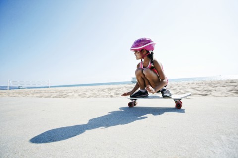 Mixed race girl riding skateboard at beach