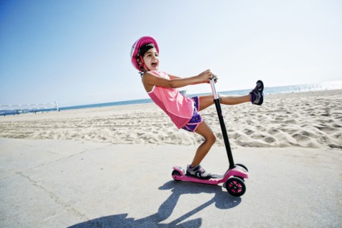 Girl riding scooter at beach