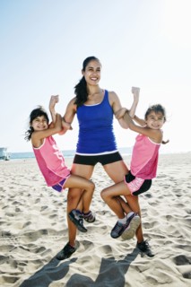 Strong mother lifting daughters at beach