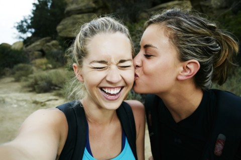 Woman kissing cheek of friend outdoors
