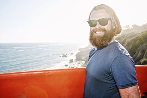 Caucasian man holding surfboard on coastal cliff