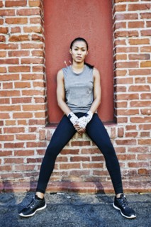 Mixed race athlete sitting on brick wall