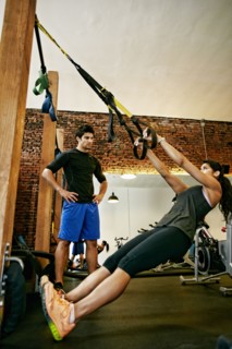 Woman working out with trainer in gymnasium