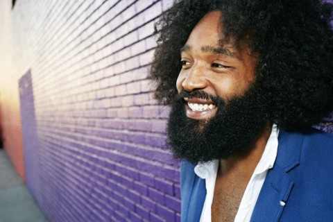 Mixed race man smiling outdoors near purple wall
