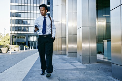 Black businessman using cell phone outside office building