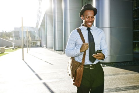 Black businessman using cell phone outside office building
