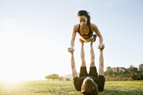 Caucasian couple doing acro yoga in park
