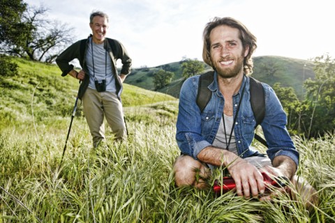 Caucasian hikers resting in grass on mountain