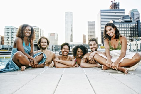Smiling friends relaxing poolside at urban swimming pool