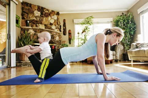 Mother working out on exercise mat with baby on legs