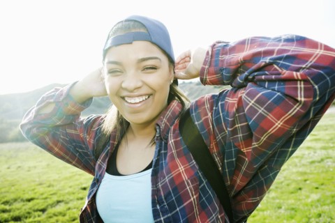 Smiling Mixed Race woman backpacking in field