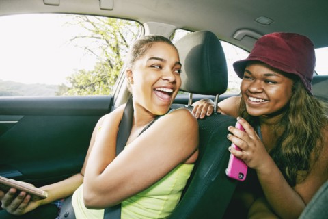 Mixed Race sisters laughing in car