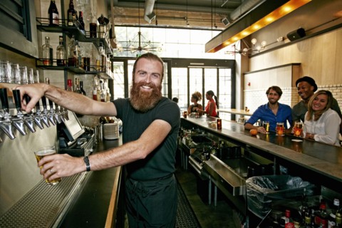 Smiling bartender pouring beer at bar
