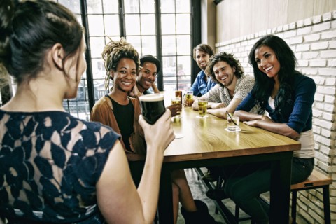 Waitress serving smiling friends at table in bar