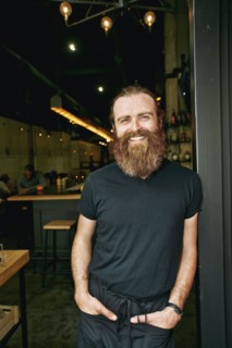 Smiling Caucasian man with beard leaning in doorway