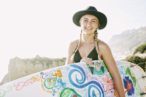 Caucasian woman carrying surfboard at beach