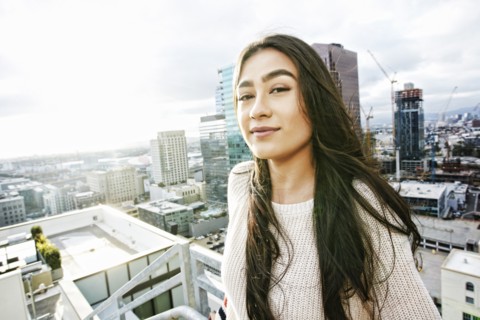 Smiling Hispanic woman posing on urban rooftop