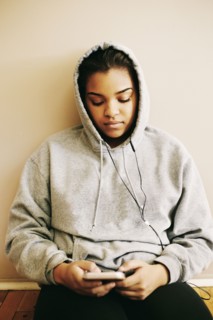 Mixed Race woman sitting on floor listening to cell phone
